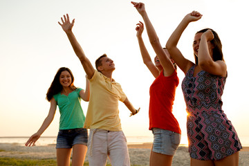 Fototapeta premium smiling friends dancing on summer beach