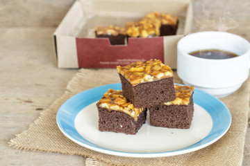 Toffee cake garnish with cashew and hot coffee on wooden table.