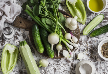 Fresh green and white vegetables - cucumbers, peppers, radish, radish, garlic, onion and olive oil, spices, and salt on a light background. Healthy vegetarian food
