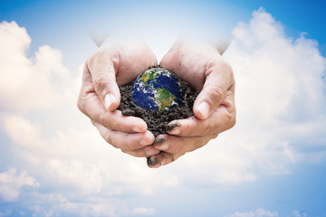 Human hands holding soil emerges from the sky in the background blurred. Create a new world. loves the world.Environment Day concept.Ecology concept. Elements of this image furnished by NASA.