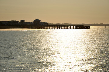 Obraz premium Sunset behind a pier with calm sea