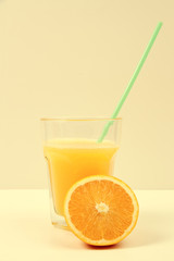 Vaso con Zumo de naranja y naranja partida a la mitad. Vista de frente. Copy space