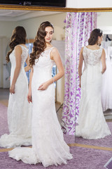 Female trying on wedding dress in a shop.