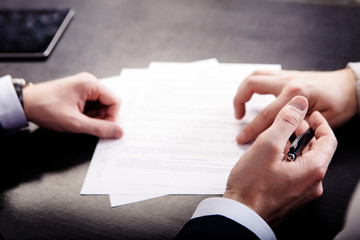 Closeup of male hand pointing where to sign a contract, legal papers or application form.