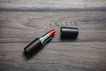 Red lipstick on black wooden table, closed-up