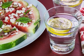 Cut watermelon pizza with crumbled feta cheese and prosciutto and basil.