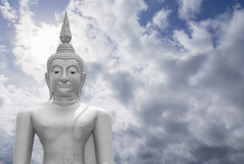 Fototapeta na wymiar white image of Buddha with blue sky and cloud in background, light effect added ,filtered image,copy space , prachuapkhirikhan,thailand