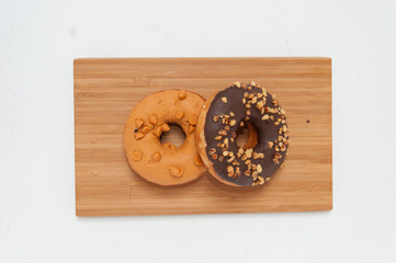 Delicious donuts with icing and tae in wood plate isolated on white