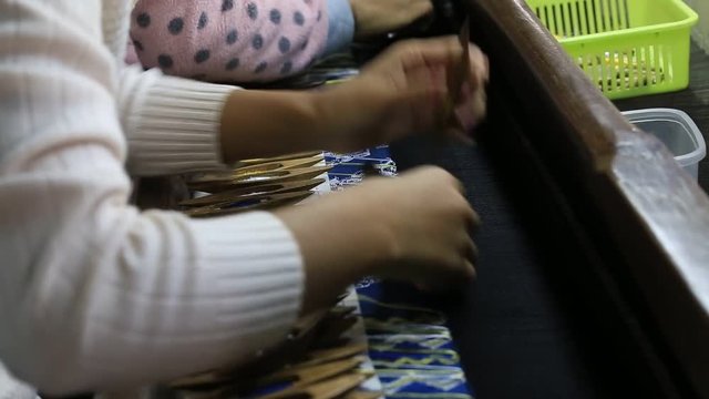 MANDALAY, MYANMAR . Traditional Burmese textile manufacture in craft village where old women work on wooden weaving loom machines and spin yarn creating silk or cotton fabric