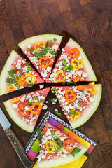 Cut vegetarian watermelon pizza with crumbled blue cheese, bell peppers and parsley.