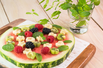Fruit watermelon pizza with fresh berries, banana, kiwi and mint