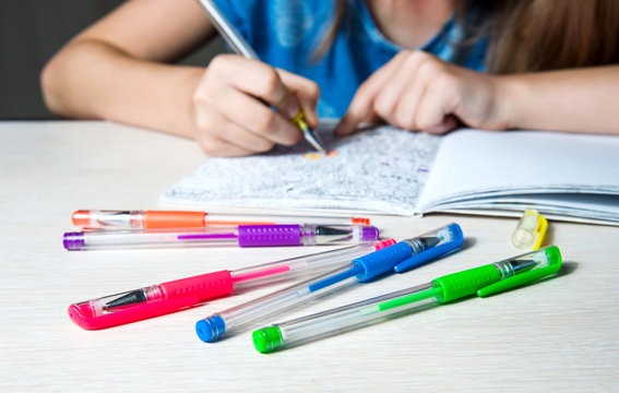 Child paint a coloring book. Coloing pens on table. Selective focus.