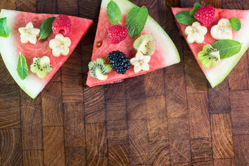 Pieces of fruit watermelon pizza with fresh berries, banana, kiwi