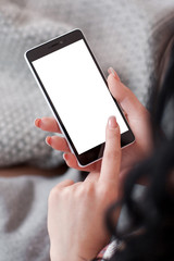 Brunette holding mobile phone with white screen. Smartphone with copyspace on screen in female hands. Woman touching empty screen of cell phone