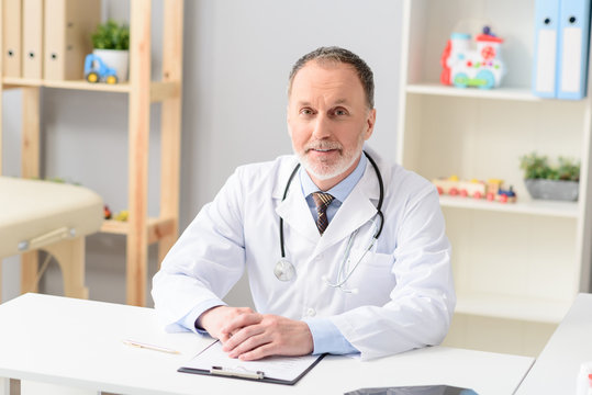 Smiling pediatrician sitting at table