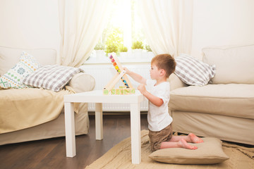 Little boy playing with abacus toy indoors