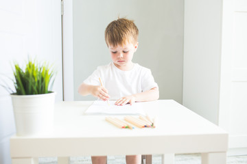 Naklejka premium Little boy with color pencils at home