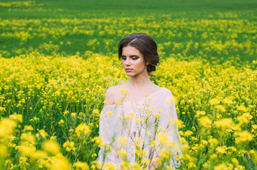 Naklejka na ściany i meble Portrait of young beautiful girl in field with yellow flowers