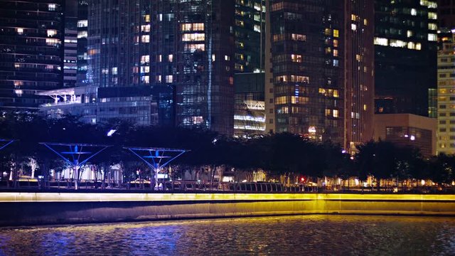 Video FullHD (1920x1080) - Evening view of downtown highrise buildings overshadowing a bayside park at night, quickly fading out of focus into a dramatic bokeh efect.