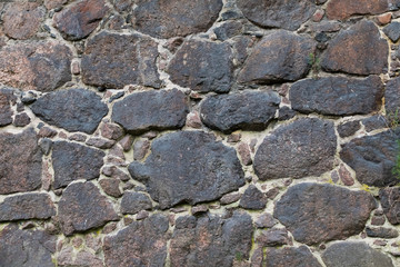 Texture is very old stone walls of the fortress. The wall of the medieval fortress of large stones. Background of cobblestones. The ancient construction of buildings from natural stones.