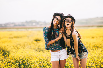 2 beautiful hippie girl in a field of yellow flowers