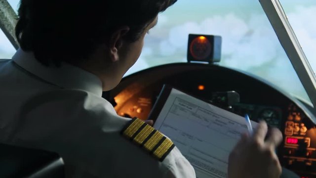 Captain filling out flight plan, plane flying in autopilot mode, pilot at work