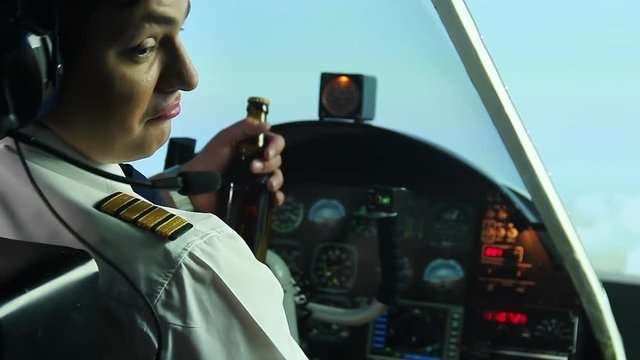 Irresponsible pilot drinking beer while operating airplane, alcohol addiction