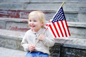 Cute toddler boy holding american flag