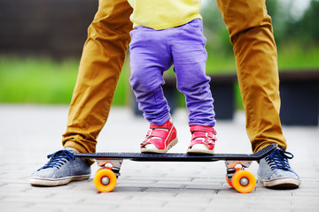 Toddler girl learning to skateboard with her father