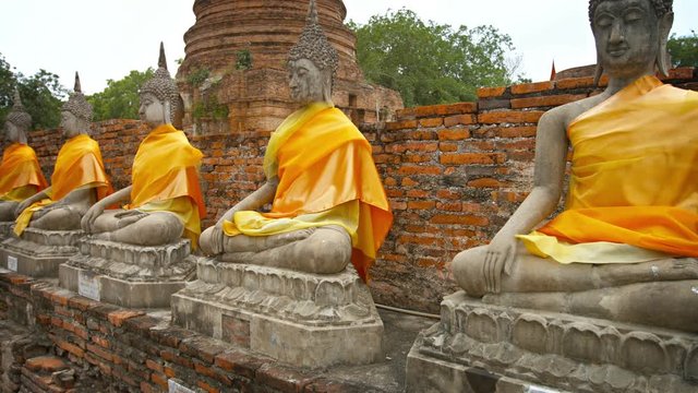 Video UltraHD - Row of stone statues of Buddha dressed in orange fabric at Wat Yai Chai Mongkhon