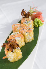 Fresh prawn and fish egg sushi rolls, with wasabi and seafood sauce, served on a green leaf plate.