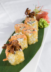 Fresh prawn and fish egg sushi rolls, with wasabi and seafood sauce, served on a green leaf plate.