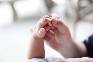 Photo of newborn baby feet and hand in soft focus