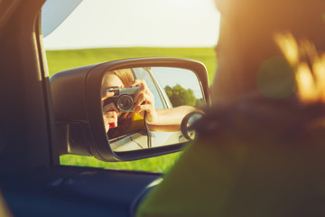 smiling girl taking photo with camera moving in car