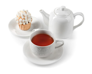 Obraz na płótnie Canvas Cup of tea with tasty cupcake and teapot, isolated on white