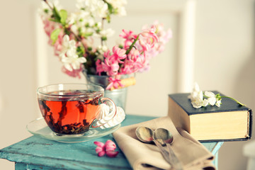 Cup of tea with flowers on wooden stool