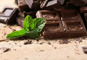 Chocolate pieces with mint leaves on wooden background