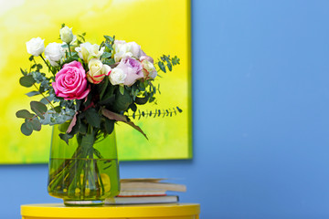Vase with fresh roses on blue wall background