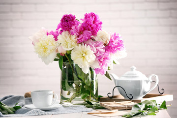Composition with beautiful bouquet of peony flowers on white brick wall background
