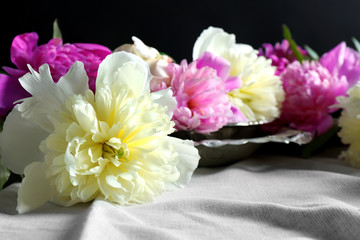 Composition with fresh peony flowers on white fabric closeup
