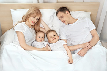 Fototapeta na wymiar Happy family on white bed in bedroom