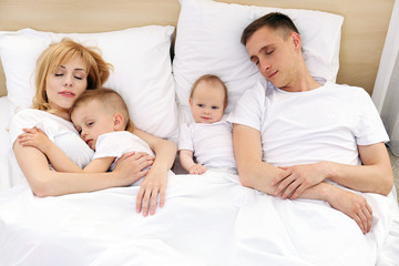Obraz na płótnie Canvas Happy family on white bed in bedroom
