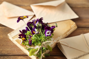 Bouquet of meadow flowers with envelope on wooden table