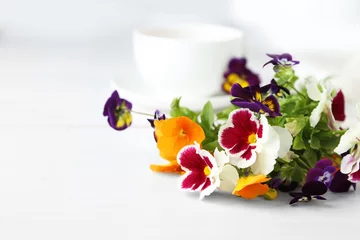 Foto op Canvas Beautiful bouquet of pansies and cup on light background © Africa Studio