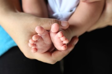 Photo of newborn baby feet and hand in soft focus