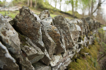 Old dry stone wall in the english countryside vanishing into the distance, with shallow depth of field