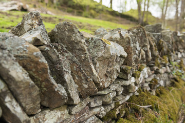 Old dry stone wall in the english countryside vanishing into the distance, with shallow depth of field