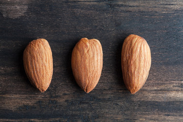 Three almonds on rustic wooden table closeup with copy space