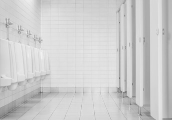 Closeup tiles wall in the toilet of man with toilet view by urinals and small room , interior at...