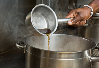 hot beef and chicken cooking stock being poured into a pan